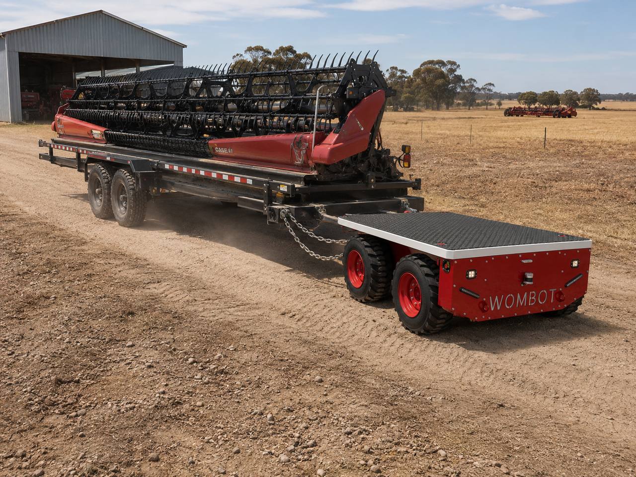 Wombot platform towing a wide agricultural header on a farm track